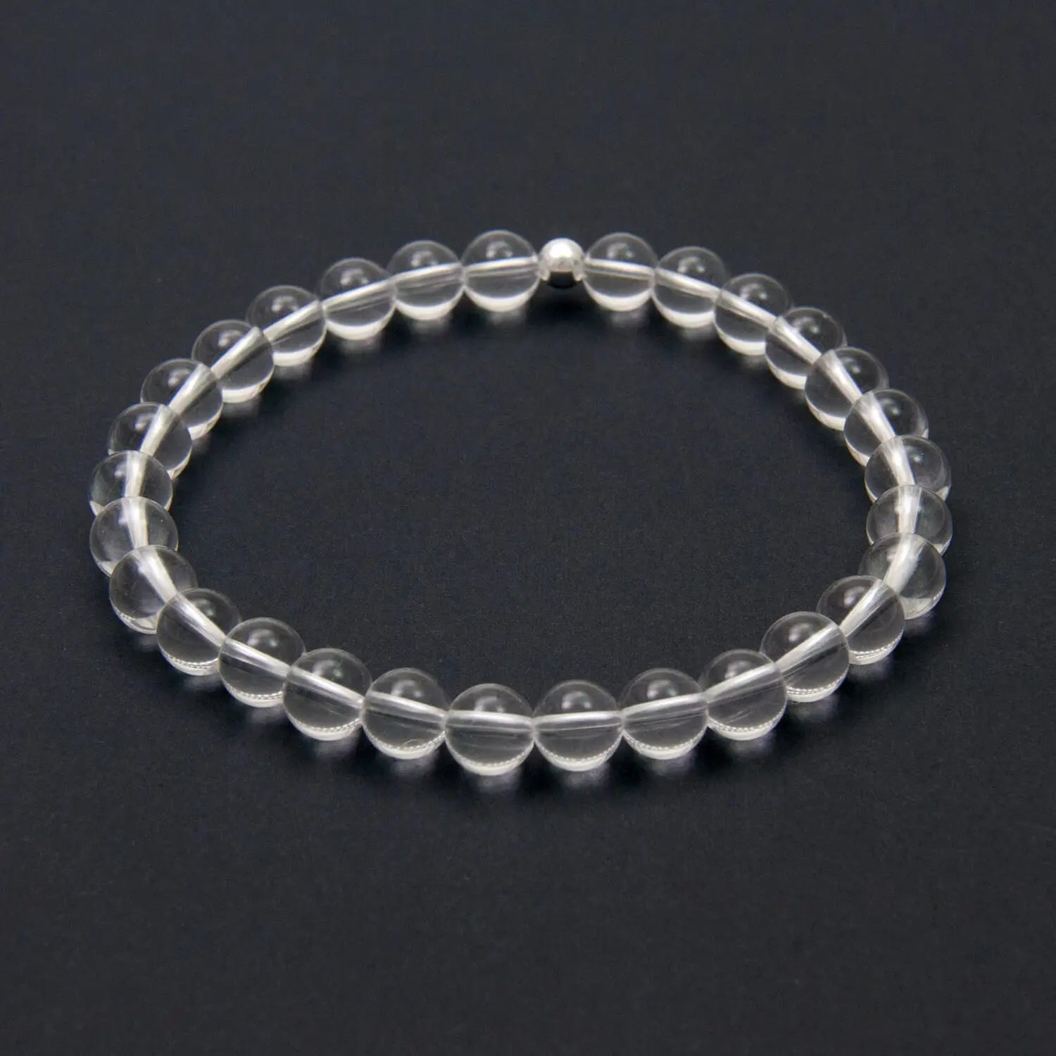 A clear quartz crystal beaded bracelet on a dark background