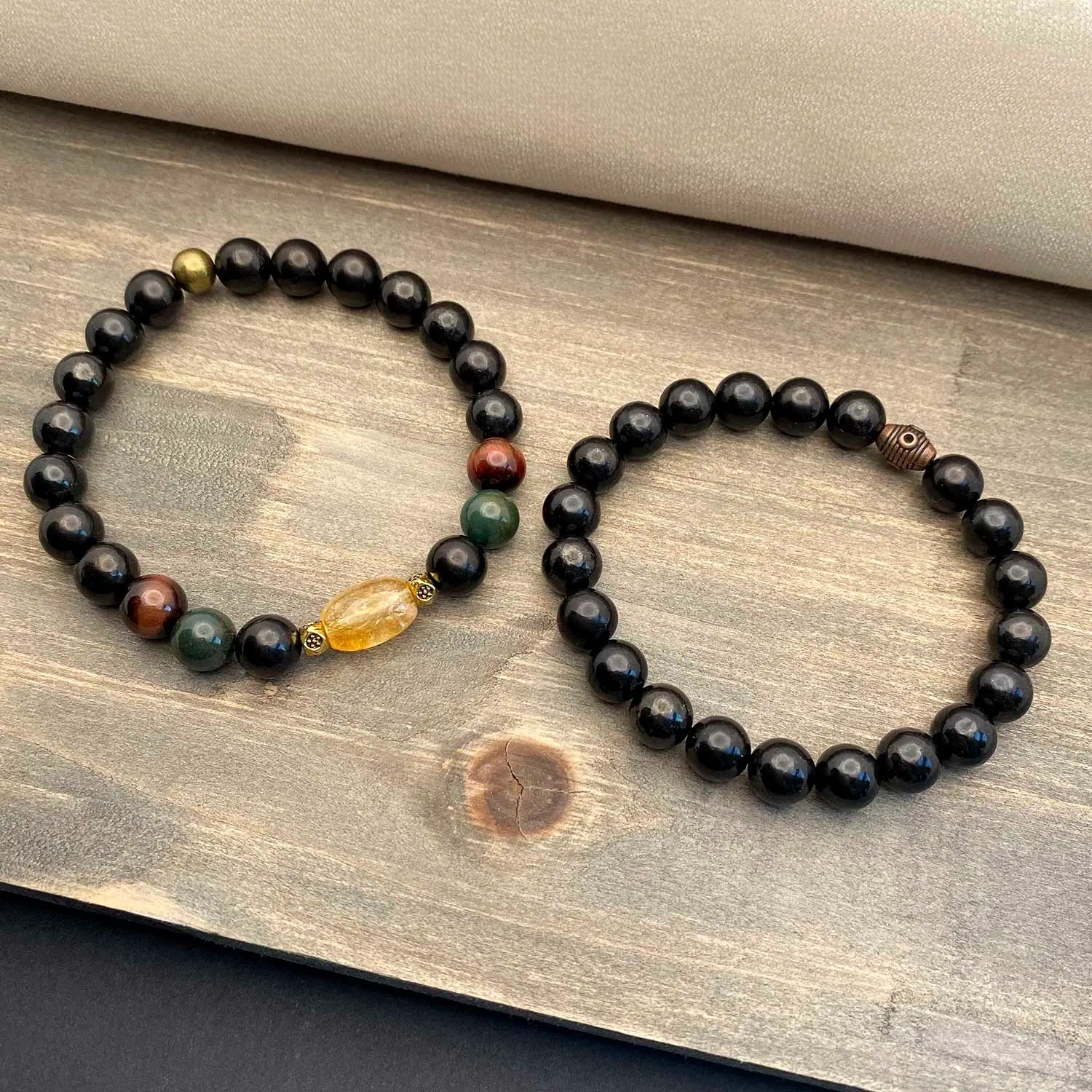 Two gemstone beaded bracelets on a wooden surface