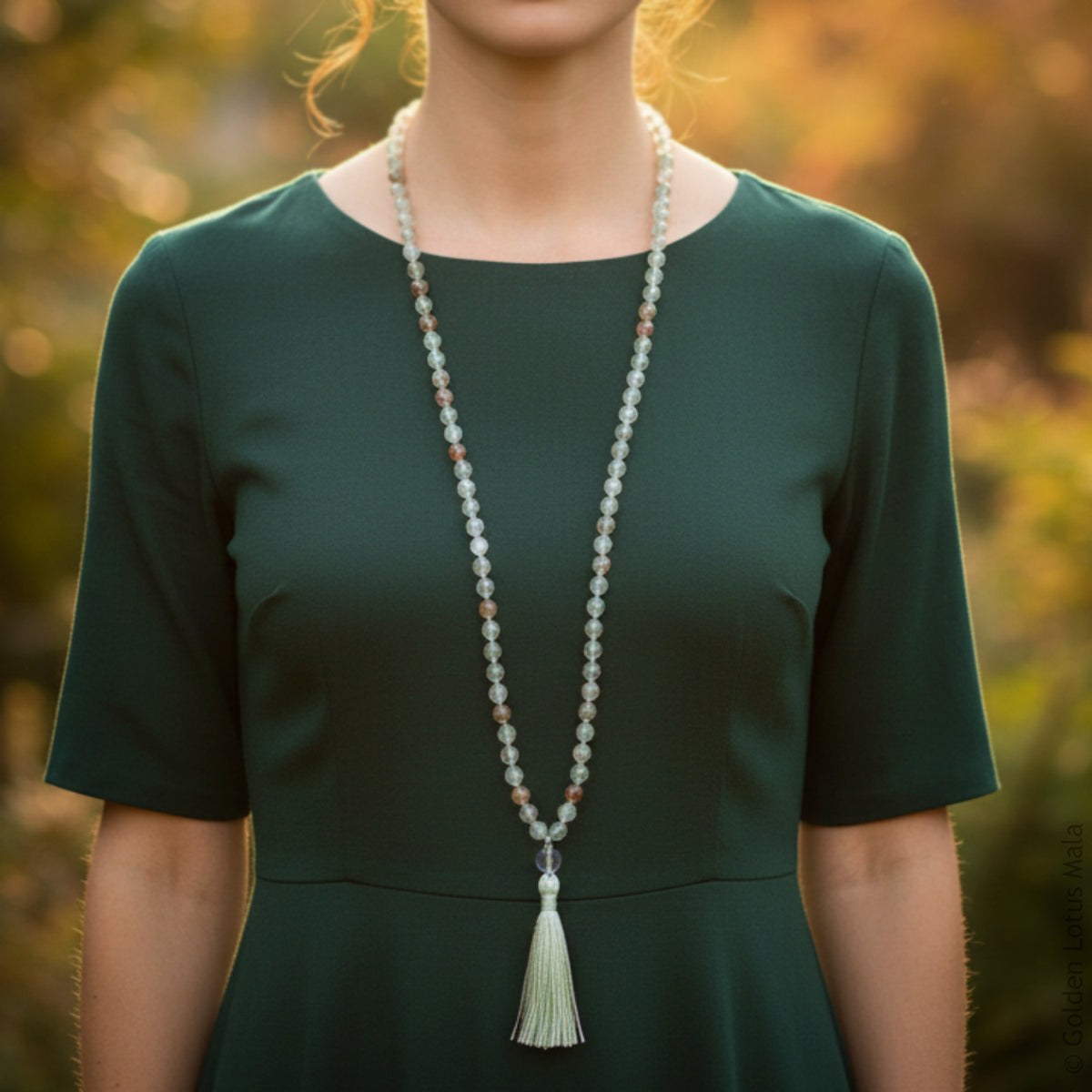 Person wearing a lodalite crystal mala with a tassel in a natural setting