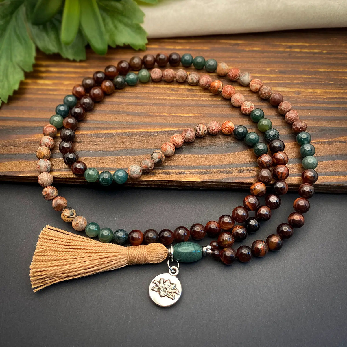 Beaded necklace with tassel and charm on a wooden surface
