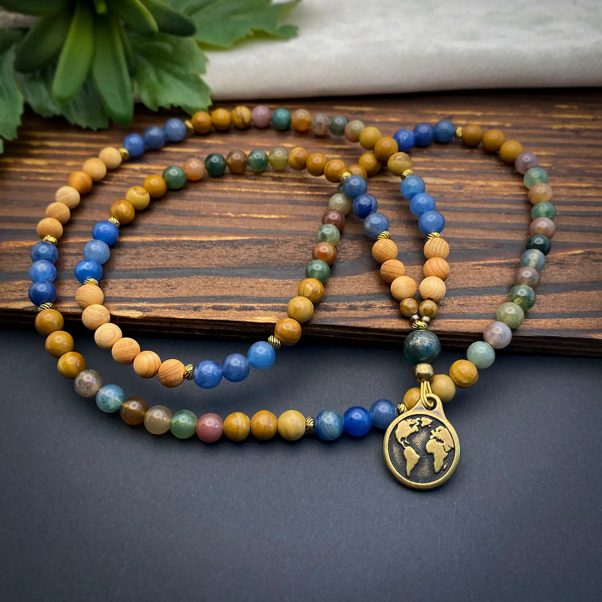 Multicolored beaded necklace with a world map pendant on a wooden surface.