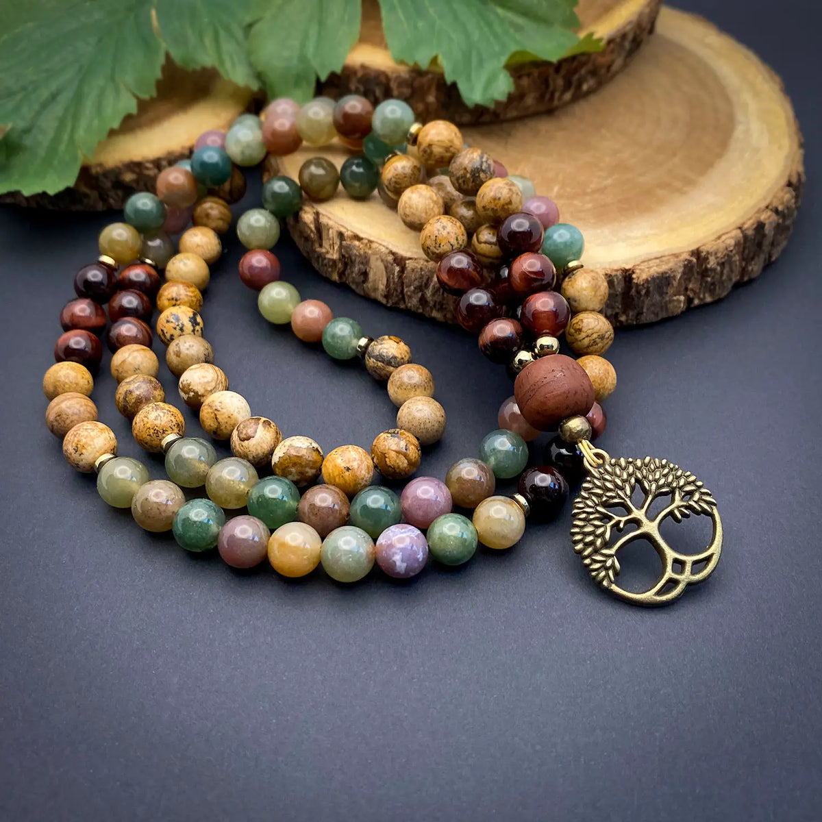 Multicolored beaded necklace with a tree of life pendant on a dark surface.