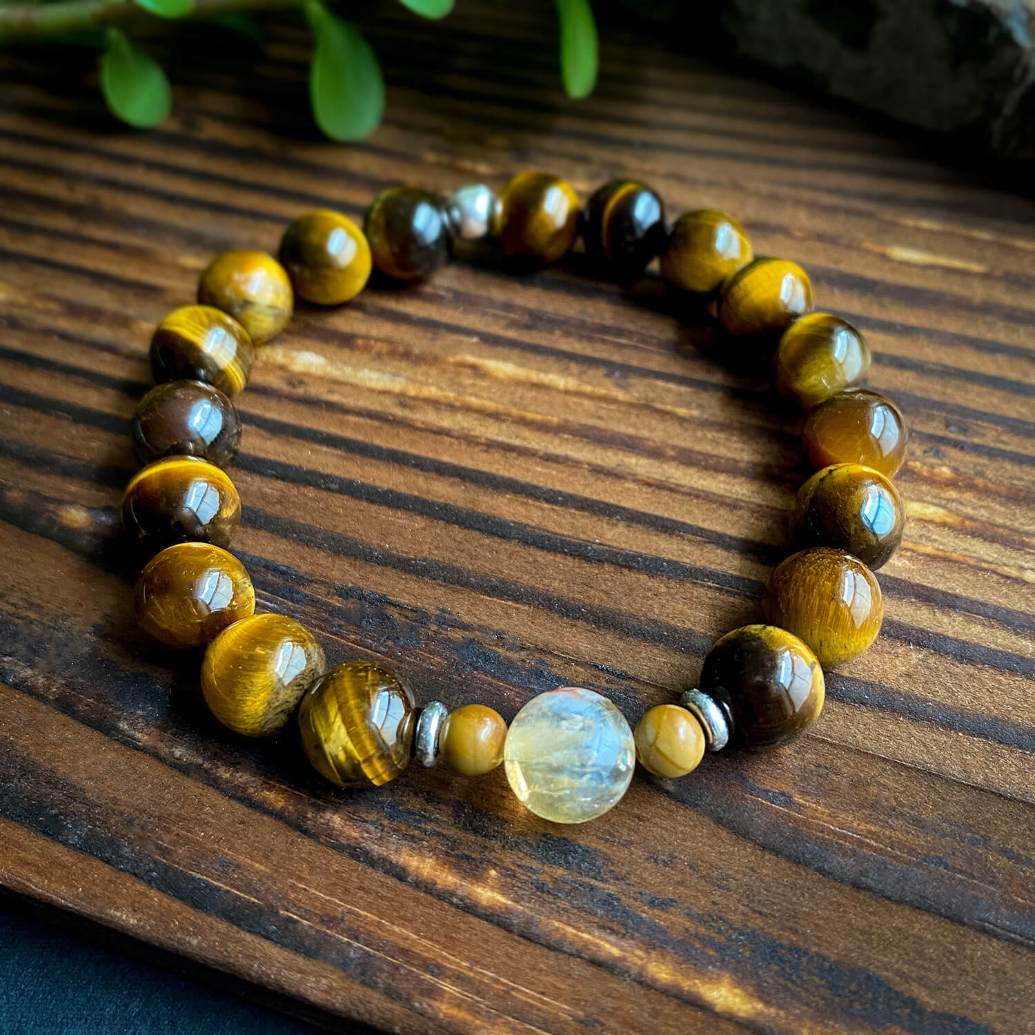 A multicolored beaded bracelet with a mix of tiger's eye and citrine stones, displayed on a wooden surface.