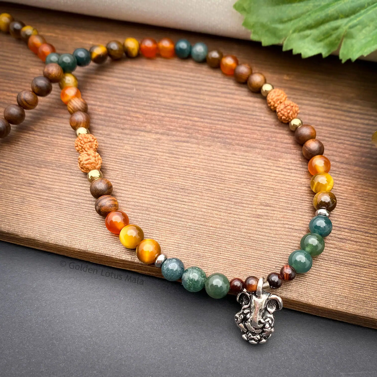 Beaded necklace with a silver elephant charp on a wooden surface