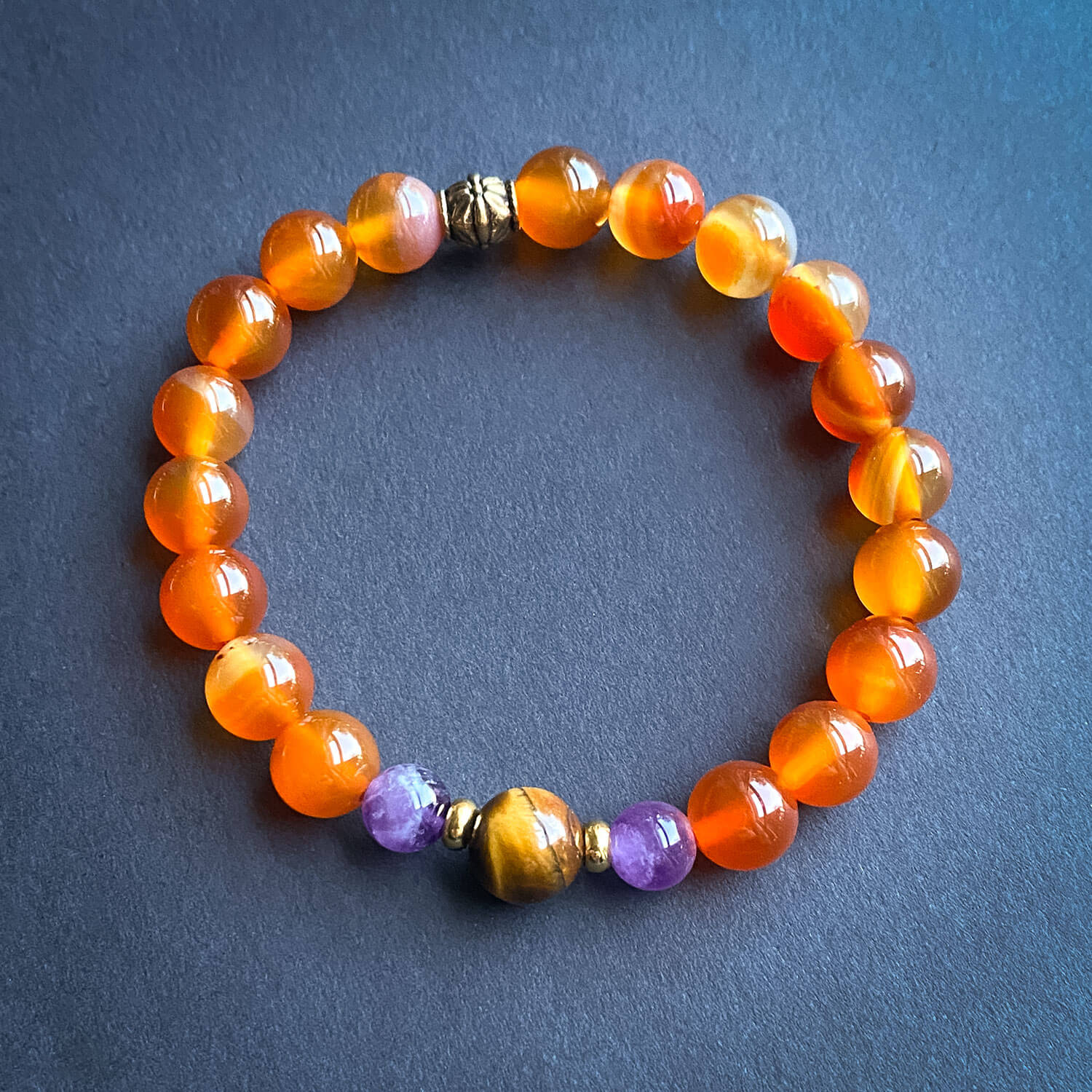 Beaded bracelet with orange, purple, and gold beads on a dark background