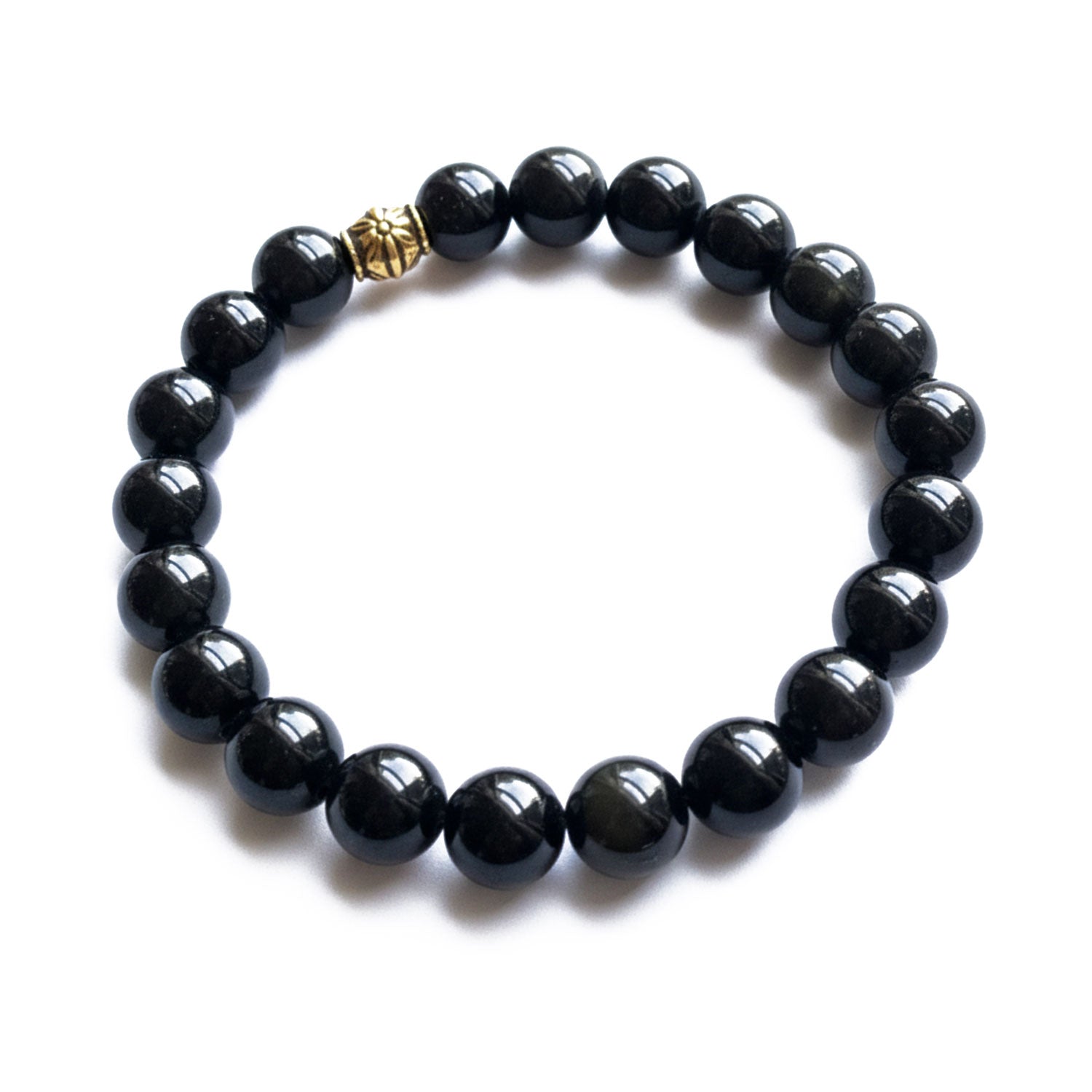 Obsidian bracelet of round beads with a gold accent on a white background