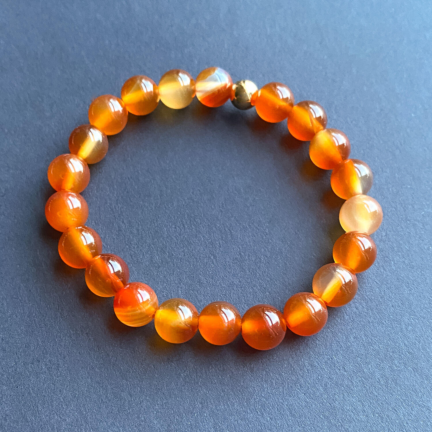 Beaded bracelet with orange carnelian beads on a dark gray background