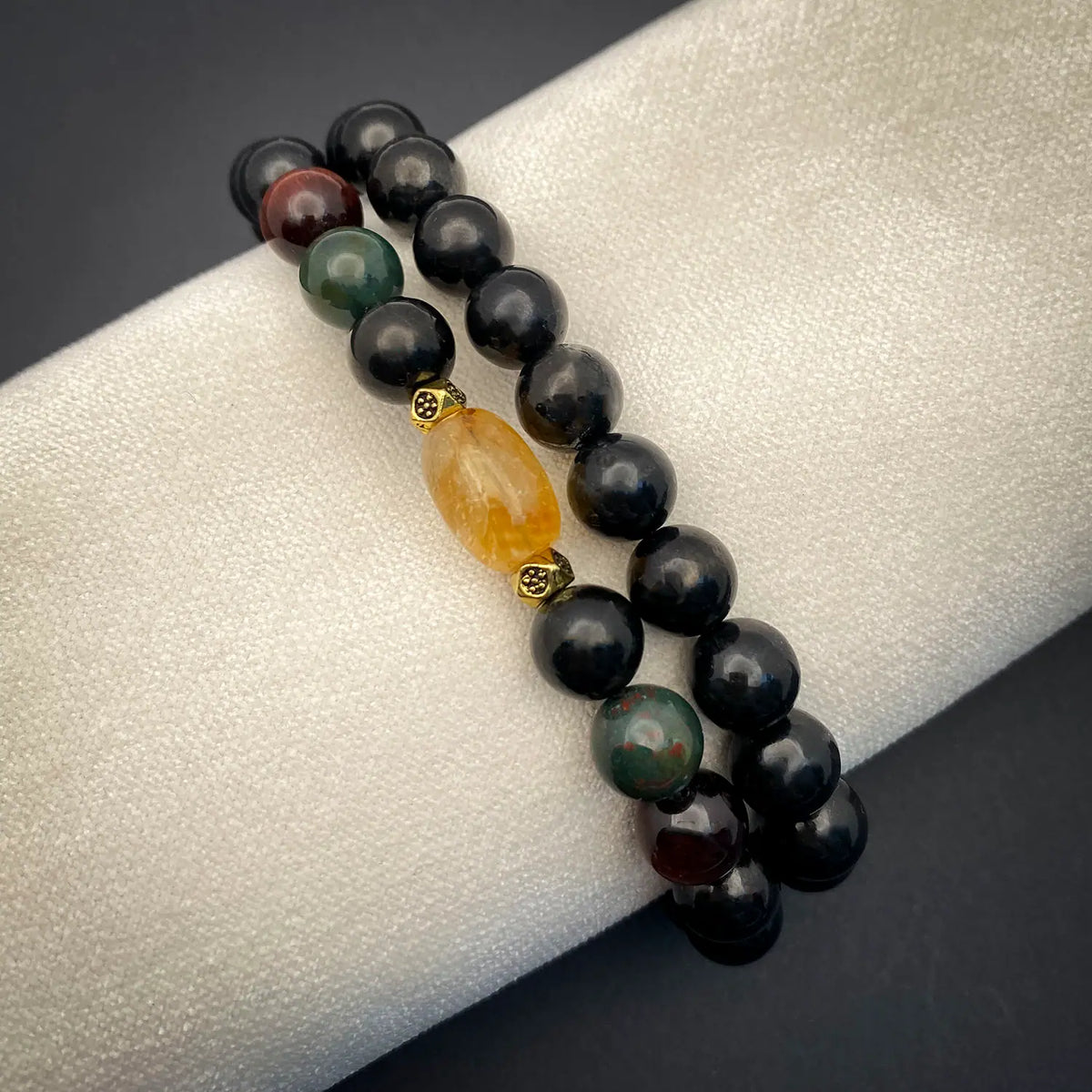 Beaded bracelets with a yellow accent stone on a gray surface