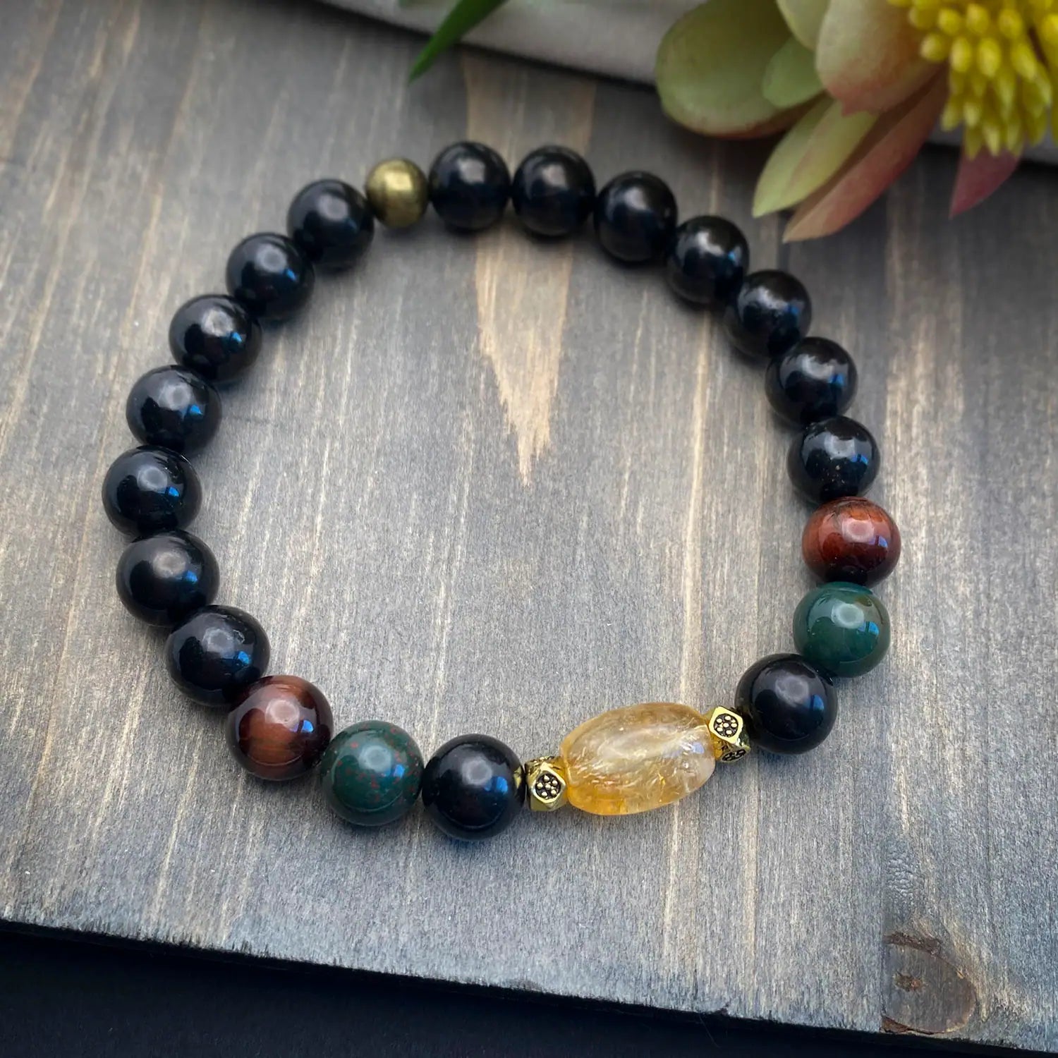 Shungite and Citrine gemstone bracelet laying on a wood table