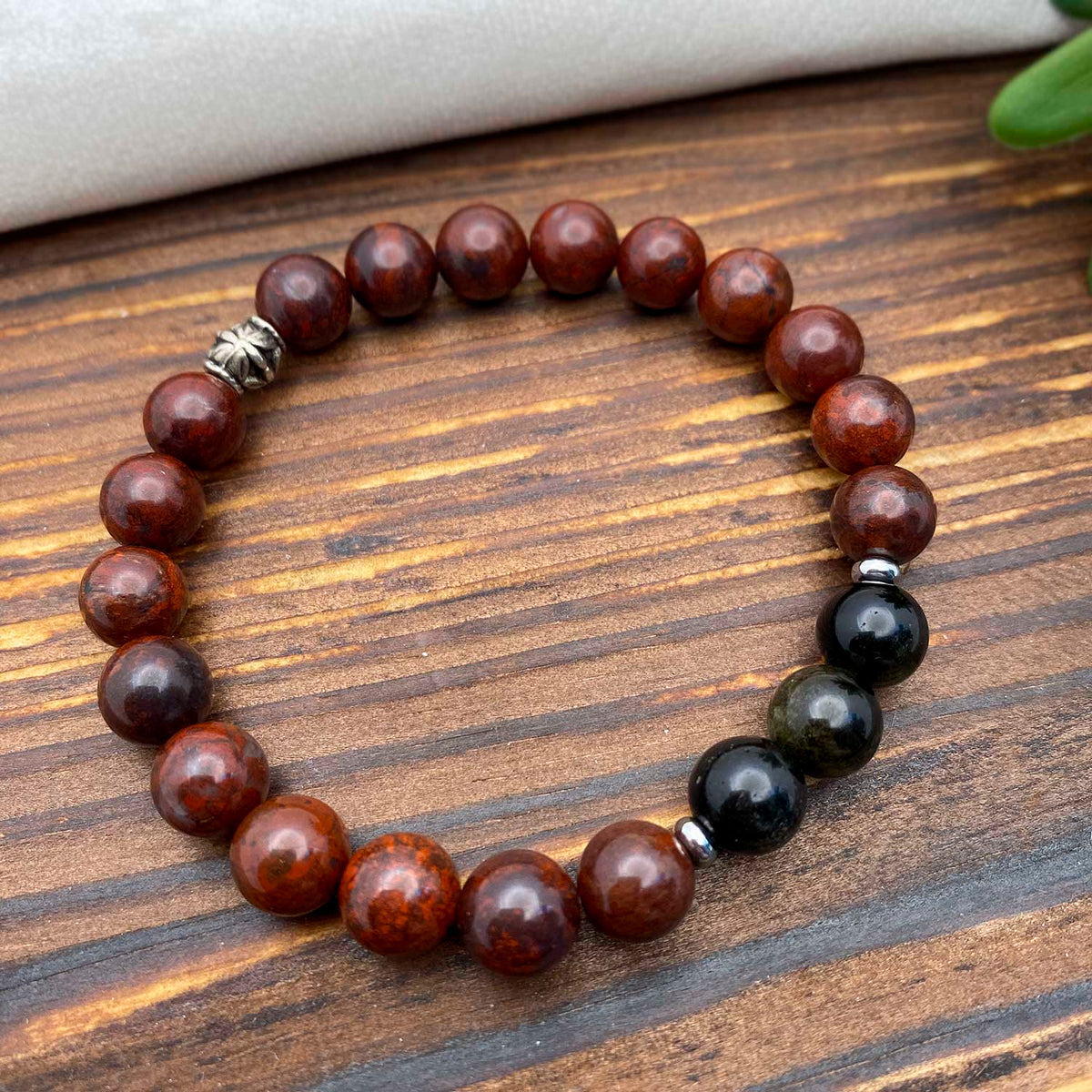 Beaded gemstone bracelet with deep red and black beads on a wooden surface