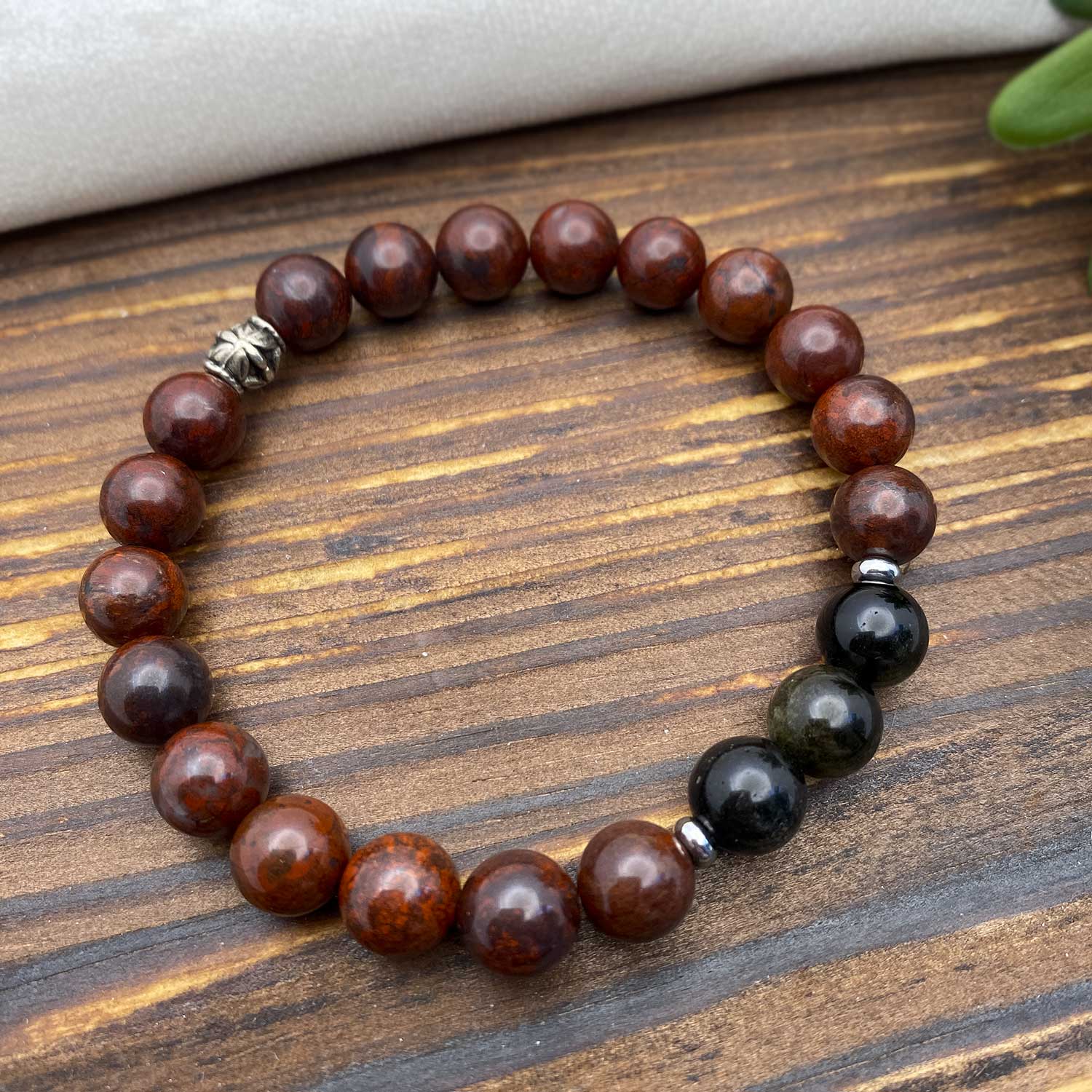 Beaded gemstone bracelet with deep red and black beads on a wooden surface