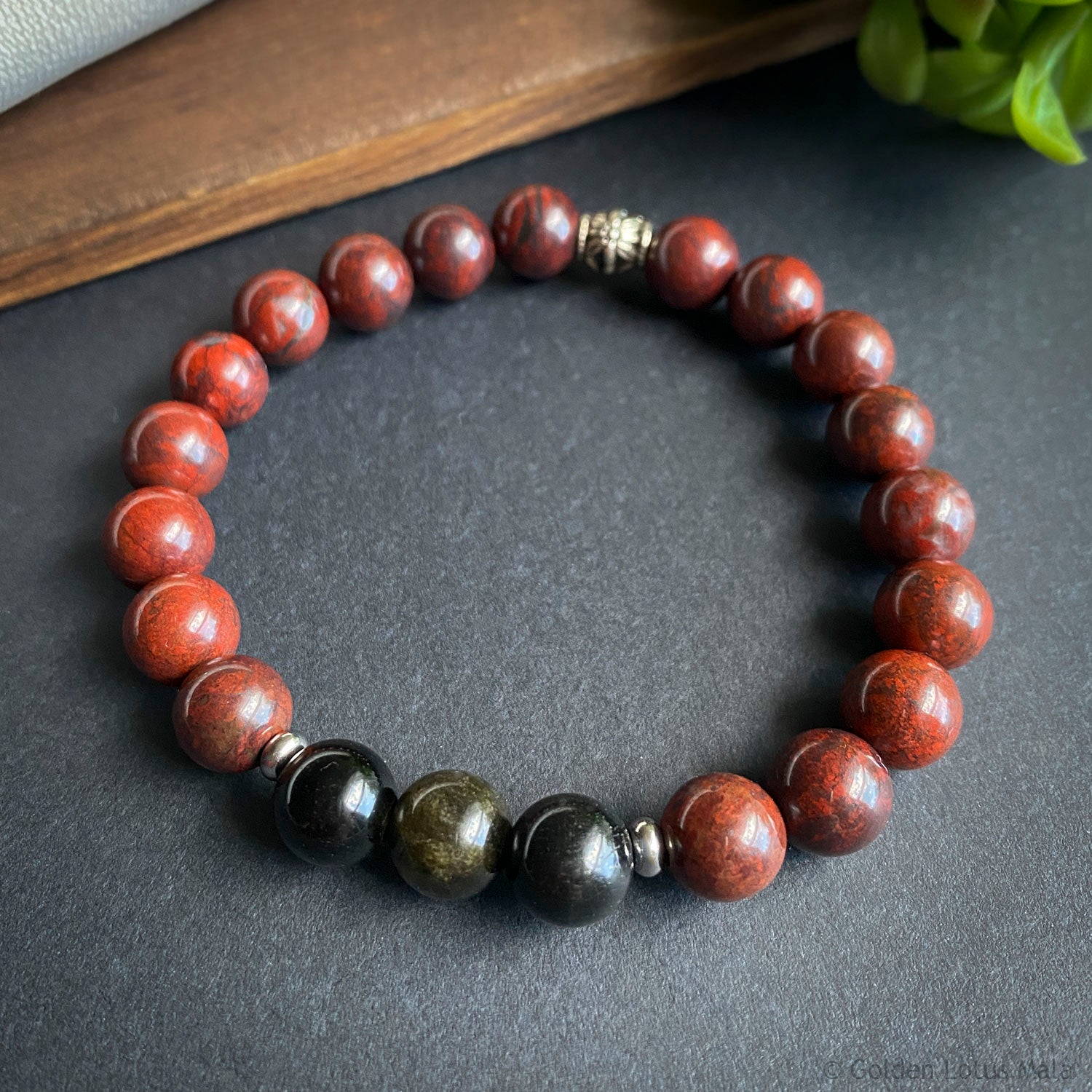 Beaded bracelet with red and black stones on a dark surface