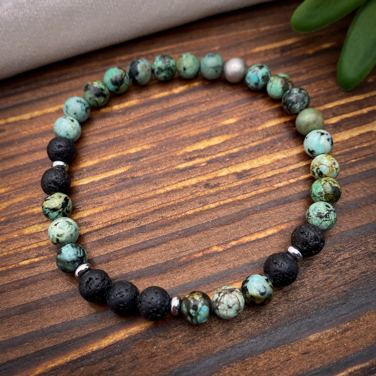 Beaded bracelet with turquoise, black, and white beads on a wooden surface
