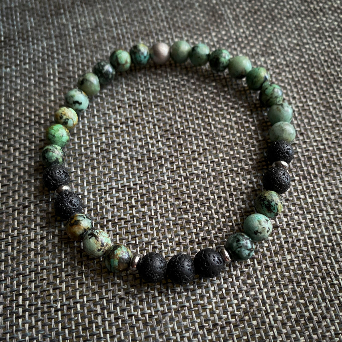 Beaded bracelet with green and black beads on a textured surface