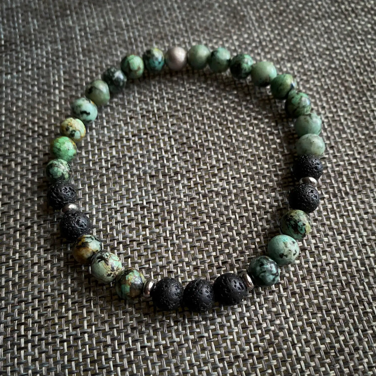 Beaded bracelet with green and black beads on a textured surface
