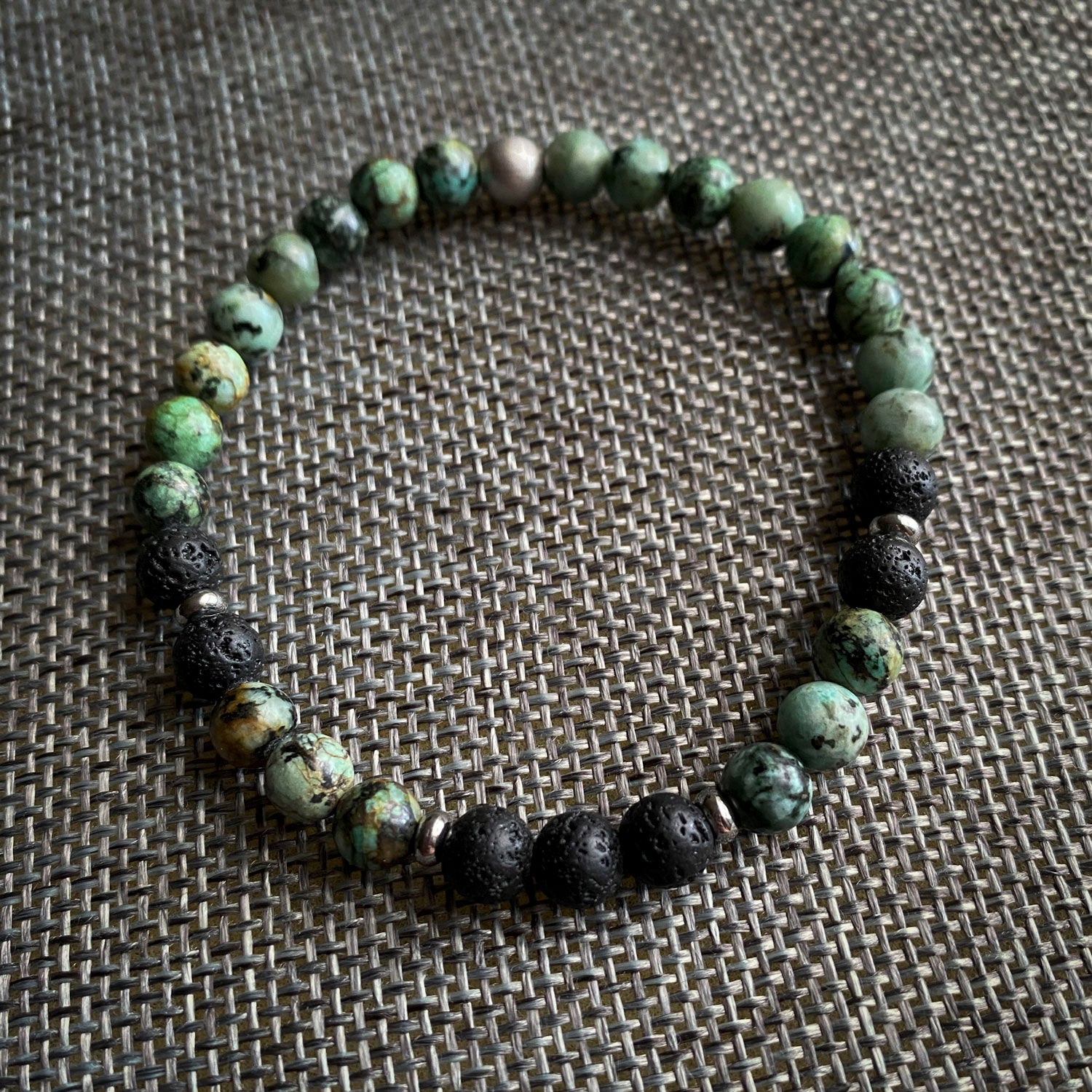 Beaded bracelet with green and black beads on a textured surface