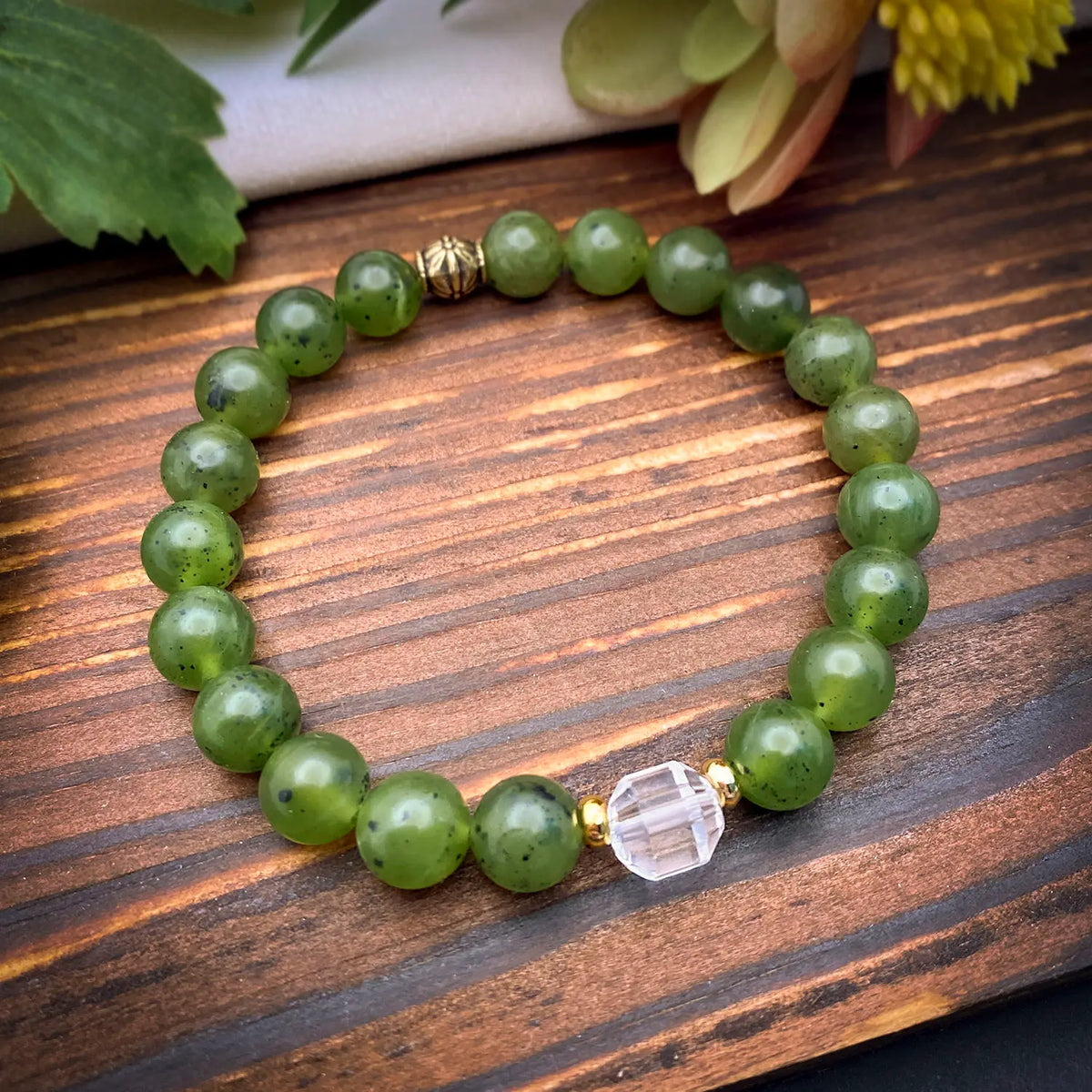Green jade bracelet with a clear crystal bead on a wooden surface