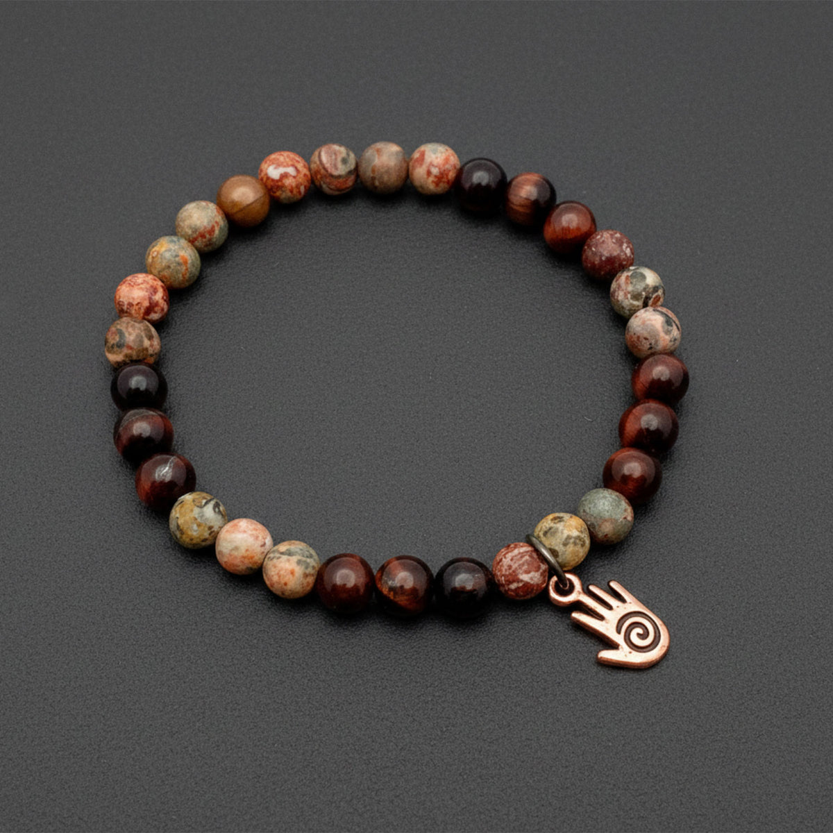 Bracelet with multicolored beads and a bronze hand charm on a dark gray background