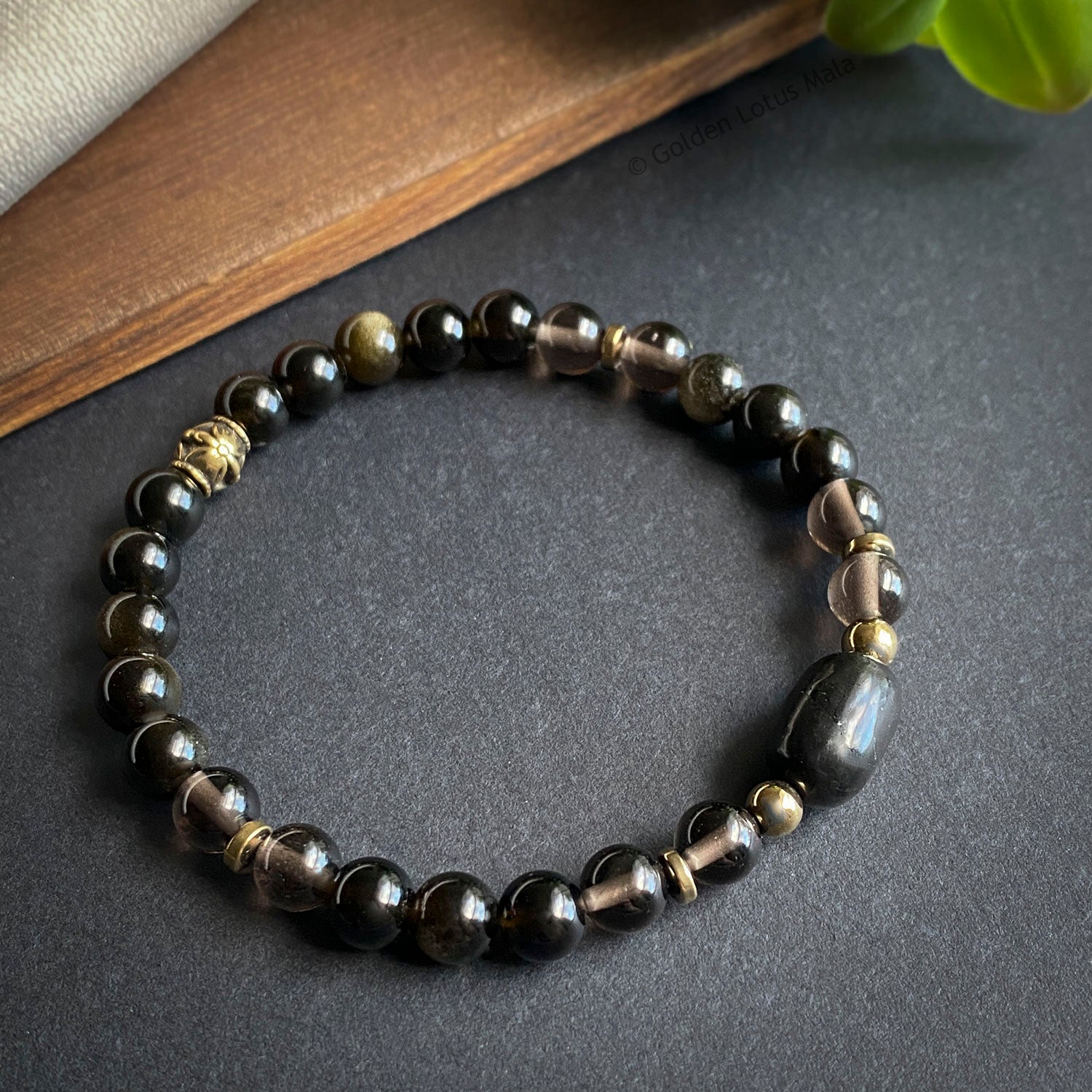 Beaded bracelet with black and gold beads on a dark surface