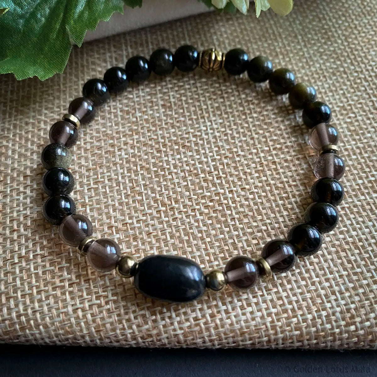 Gemstone beaded bracelet with black and gold beads on a textured fabric background