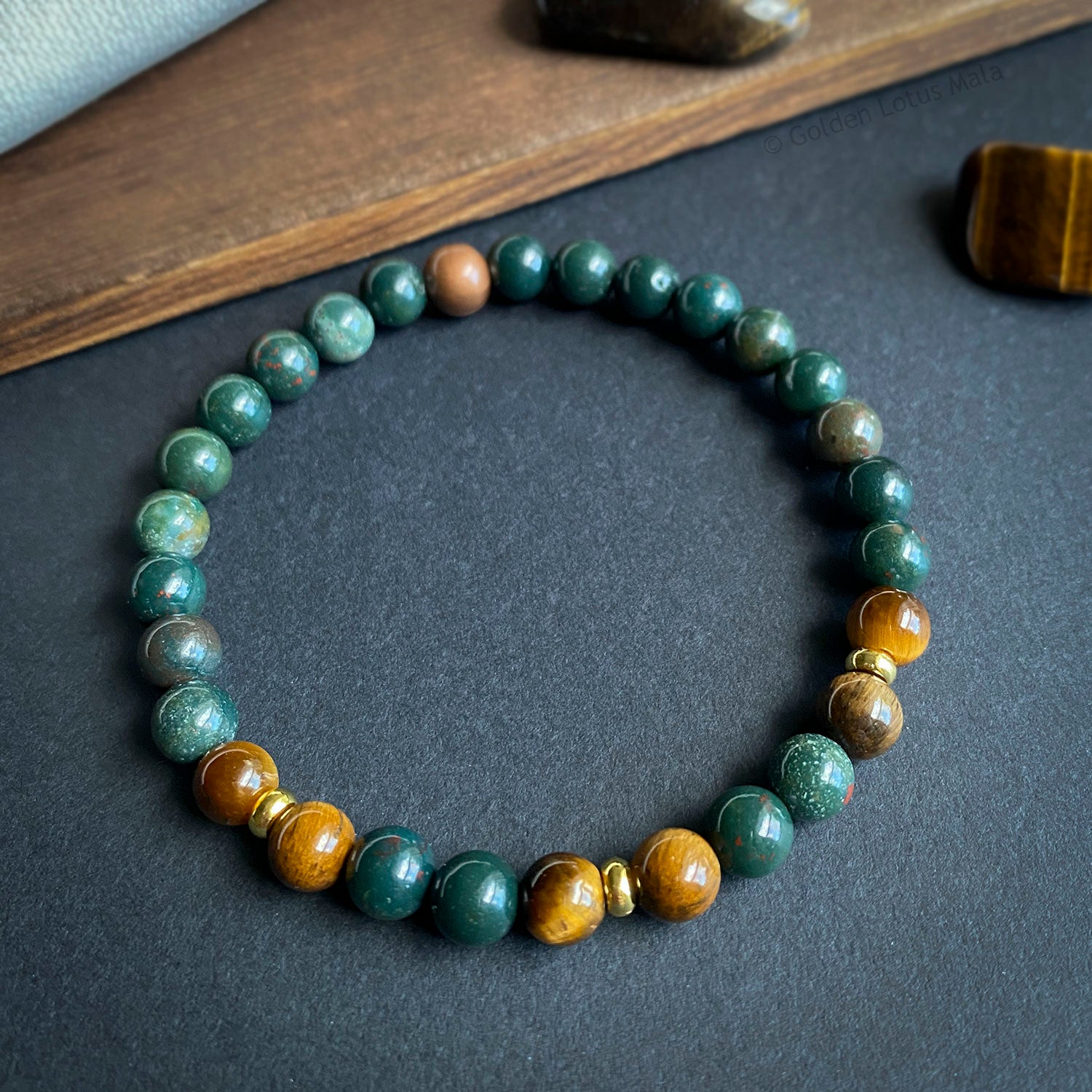 Beaded bracelet with green and brown stones on a dark surface