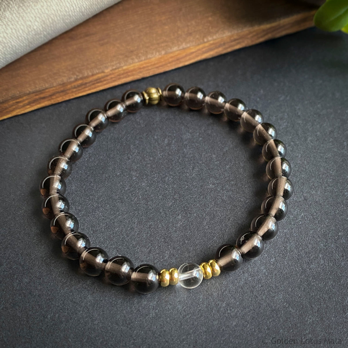 Beaded bracelet with black and gold beads on a dark surface
