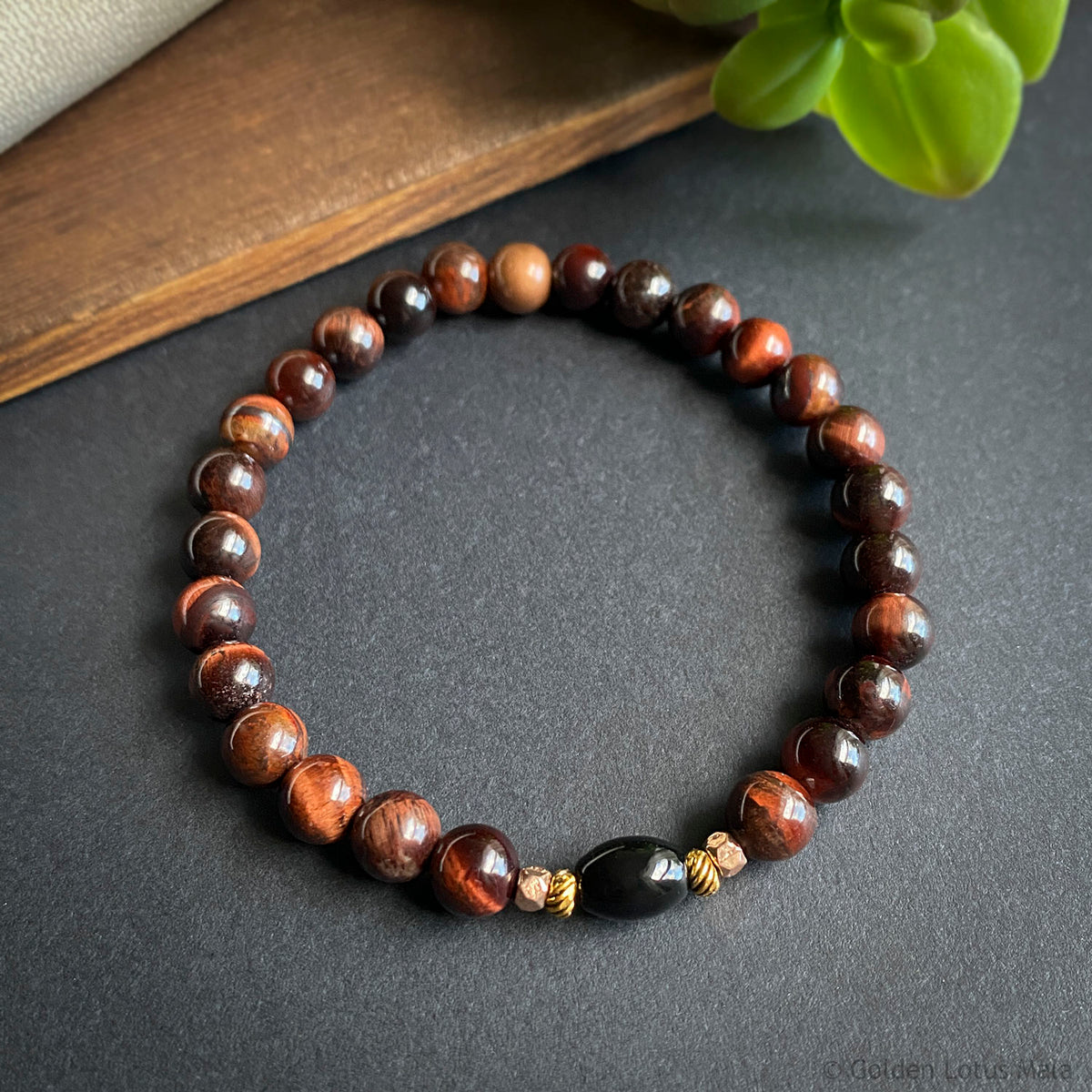 Beaded bracelet with red-brown and black stones on a dark surface