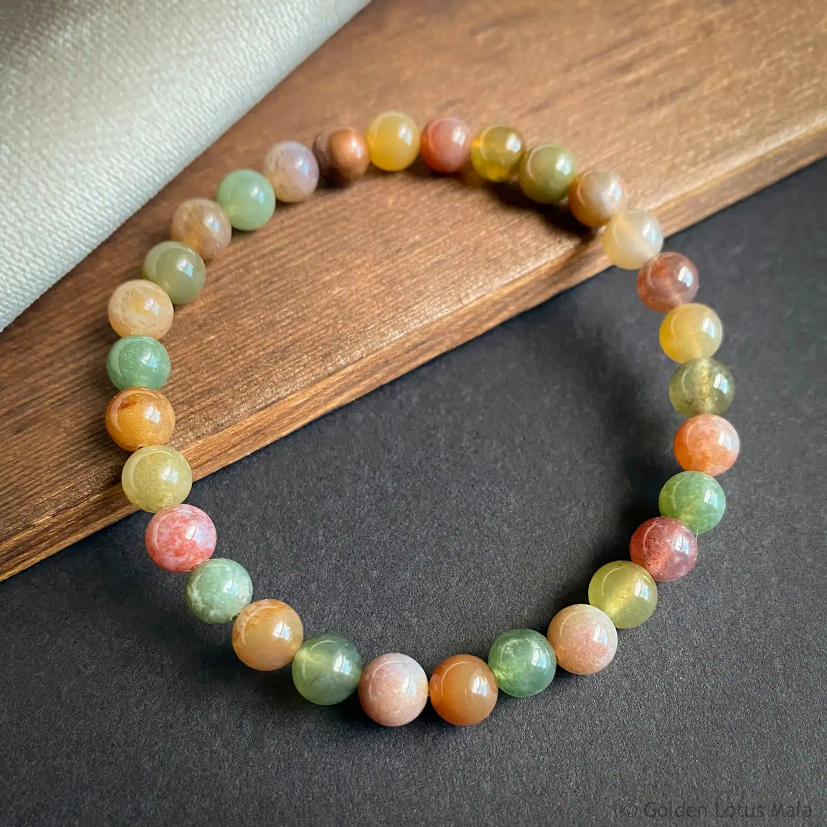 Multicolored agate gemstone bracelet on a wooden and gray surface
