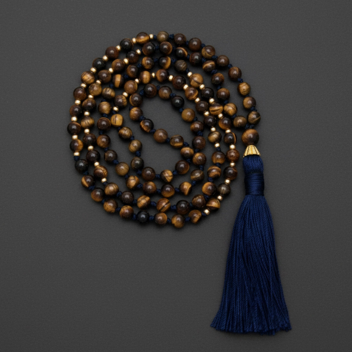 Meditation tigerseye mala necklace with a blue tassel on a dark gray background