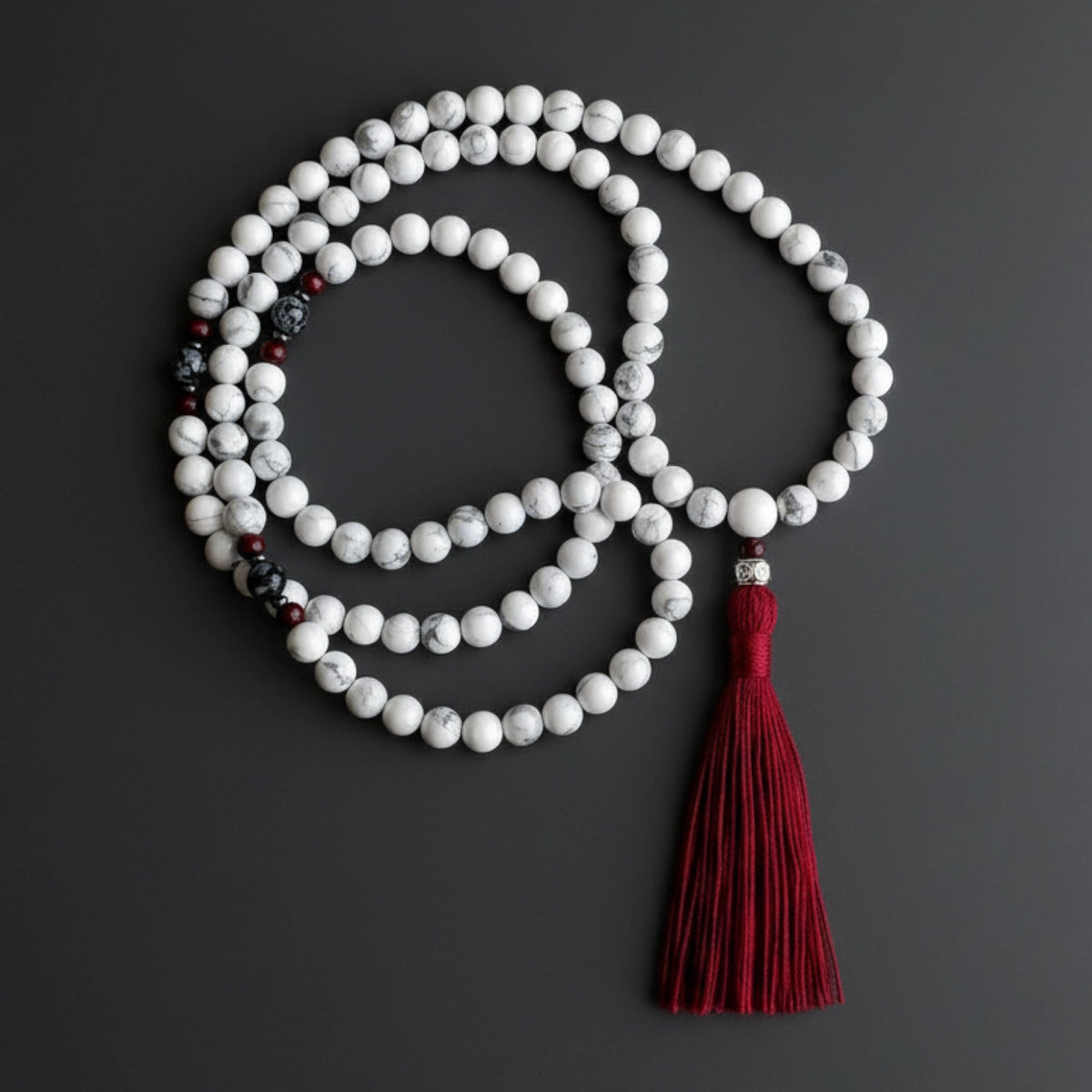 Meditation beads with a red tassel on a dark background