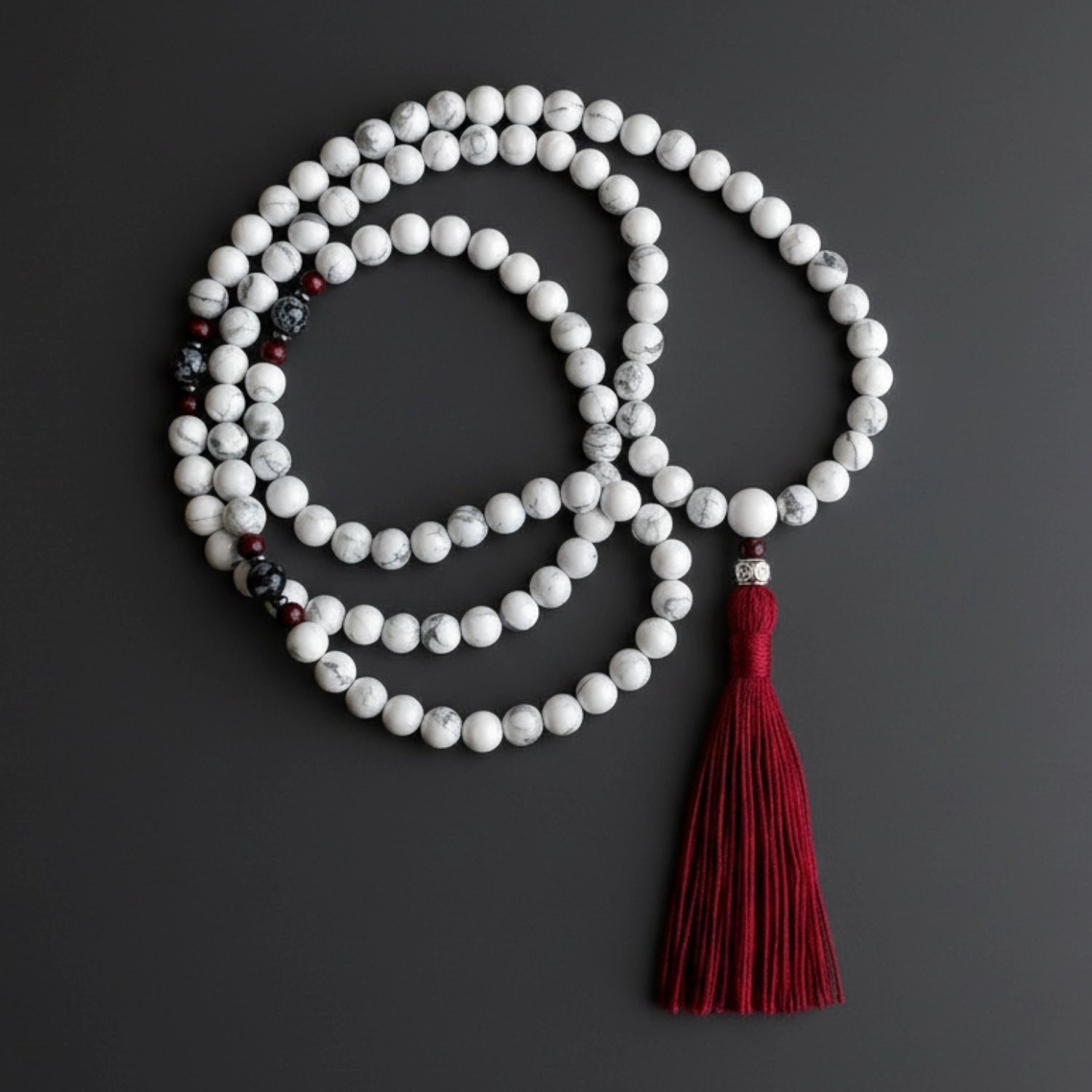 Meditation beads with a red tassel on a dark background