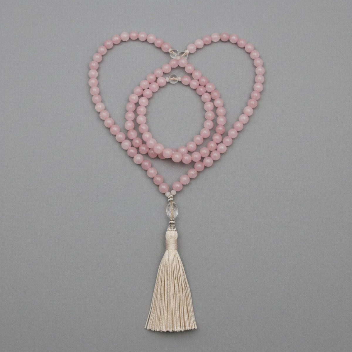 Pink mala necklace with a tassel on a gray background