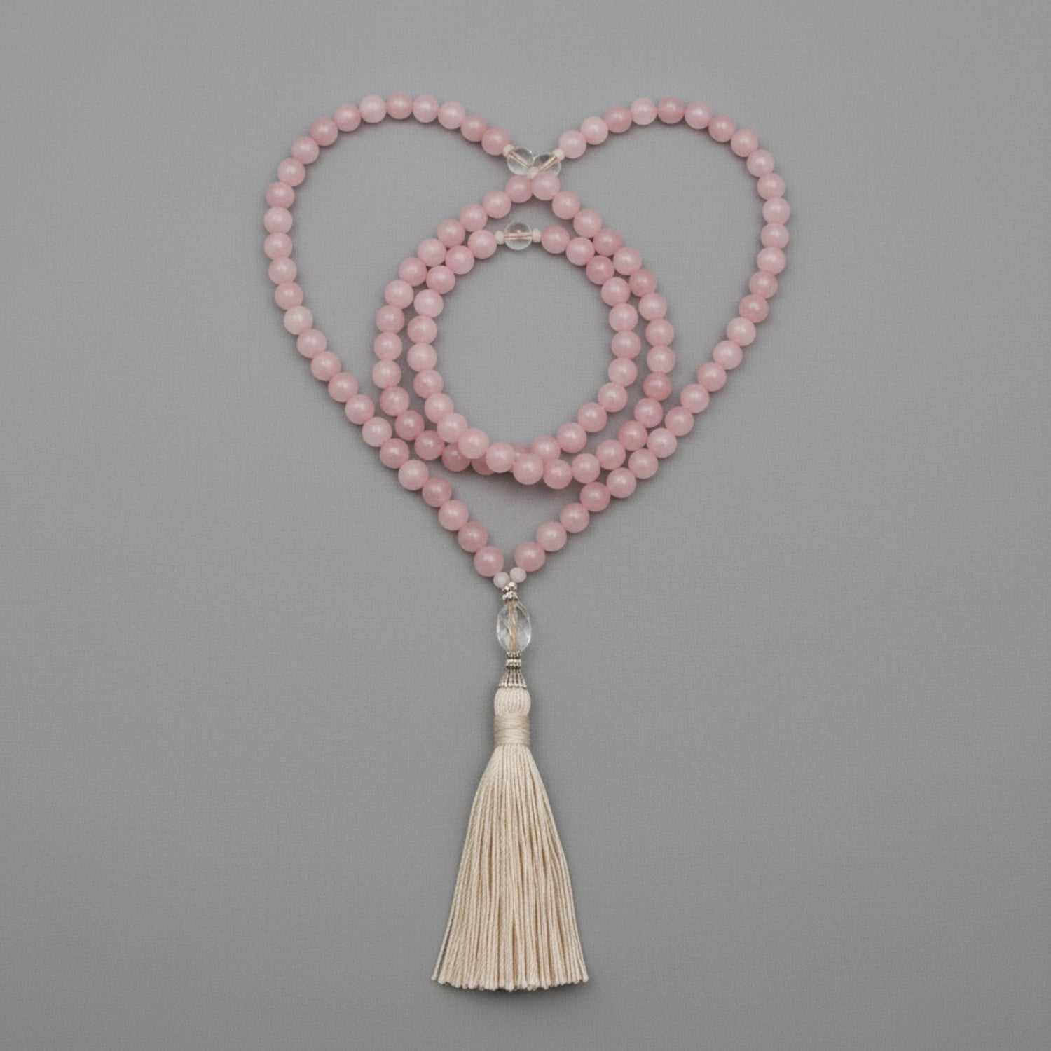 Pink mala necklace with a tassel on a gray background