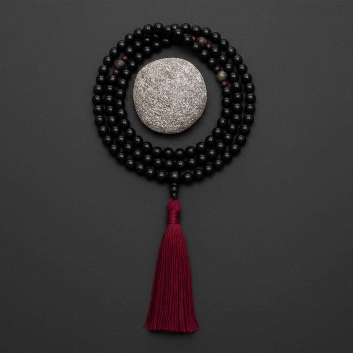 Black onyx mala necklace and red tassel on a dark background