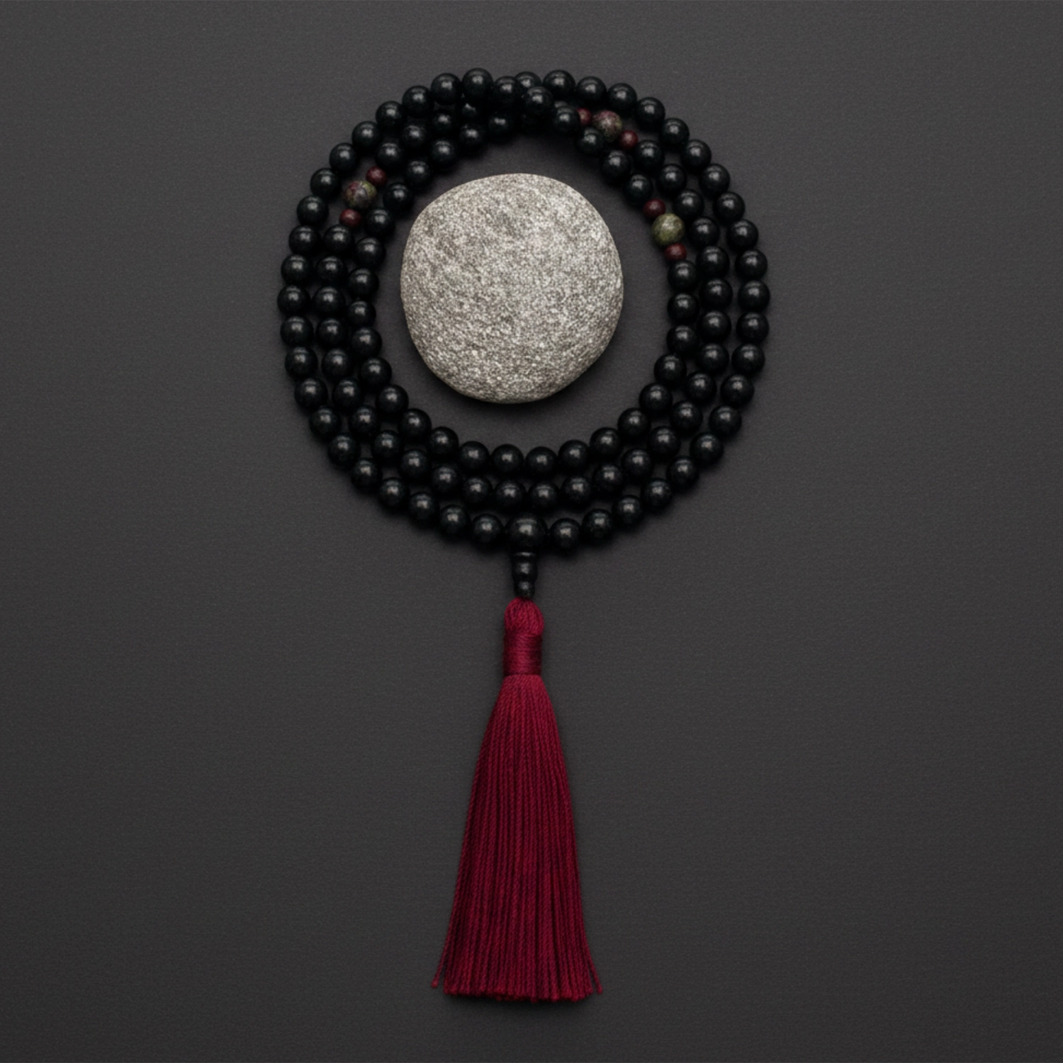 Black onyx mala necklace and red tassel on a dark background
