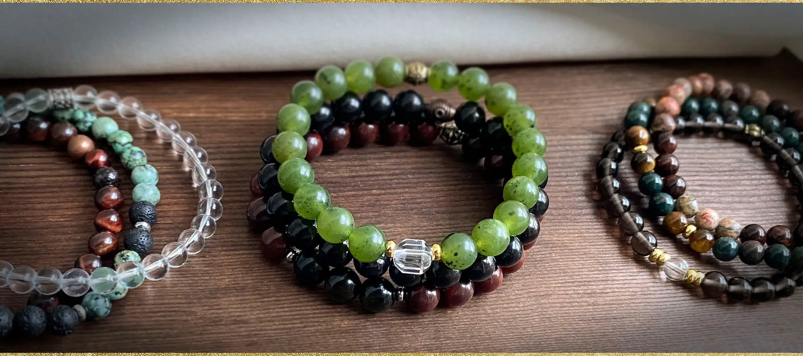 A variety of gemstones bracelets made by Golden Lotus Mala displayed on a wooden surface.