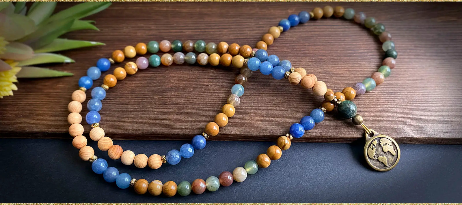 The Earth Mala a colorful beaded necklace with an Earth pendant on a wooden surface.
